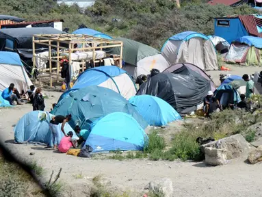 Imigran gelap berjalan di dekat puluhan tenda yang didirikan di sebuah kamp sementara di sekitar pelabuhan Calais, Prancis, Minggu (2/8/2015). Sebelumnya, ratusan imigran memaksa masuk Prancis melalui Terowongan Channel. (AFP PHOTO/FRANCOIS LO PRESTI)