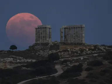 Bulan Purnama Stroberi atau Strawberry Full Moon muncul di belakang Kuil Poseidon marmer kuno di Cape Sounion, sekitar 70 Km selatan kota Athena, Yunani, Kamis (24/6/2021). Strawberry Full Moon adalah istilah yang diambil dari cerita tradisi dari suku-suku asli Amerika (AP Photo/Petros Giannakouris)