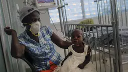 Seorang pasien COVID-19 bersandar pada kaki ibunya di Rumah Sakit Anak Saint Damien Port-au-Prince, Haiti, Minggu (24/10/2021). Dilanda krisis, rumah sakit pediatri utama ibu kota hanya memiliki bahan bakar yang tersisa 3 hari untuk menjalankan ventilator dan peralatan medis. (AP/Matias Delacroix)