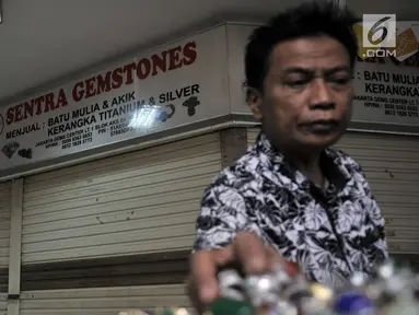 Pengunjung melihat koleksi batu akik di salah satu kios yang masih bertahan di Pasar Rawa Bening, Jakarta, Senin (10/9). Sepinya pembeli menyebabkan banyak kios pedagang batu akik tutup akibat gulung tikar. (Merdeka.com/Iqbal S. Nugroho)