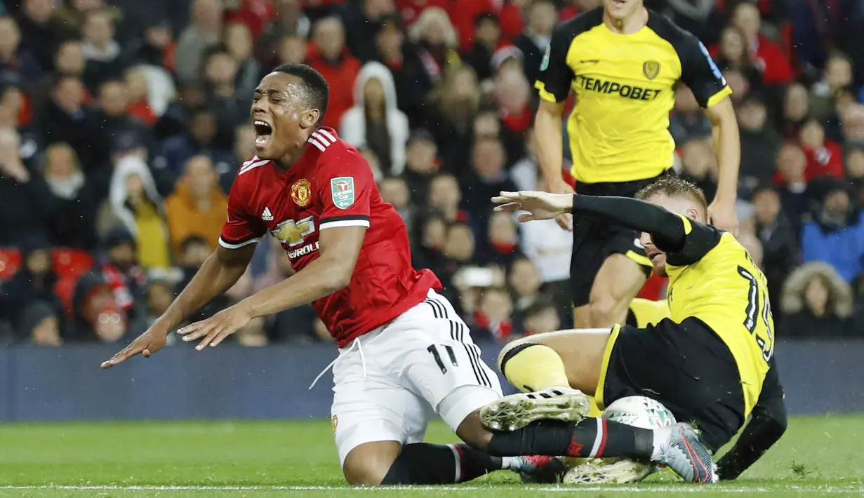 Pemain Manchester United, Anthony Martial (kiri) terjatuh saat berebut bola dengan pemain, Burton Albion, Tom Naylor pada laga Piala Liga Inggris di Old Trafford, Manchester (20/9/2017). MU menang 4-1. (Martin Rickett/PA via AP)