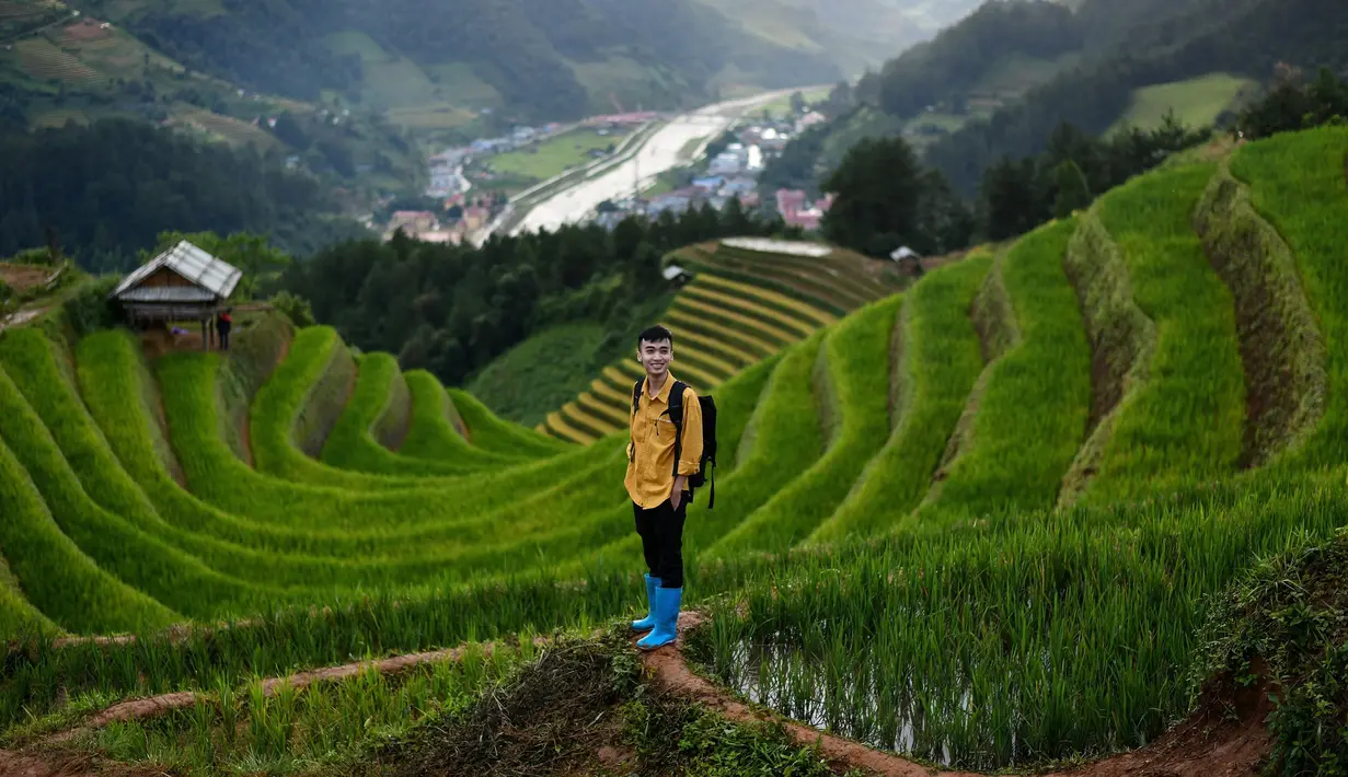 Pengunjung berfoto dengan latar belakang sawah terasering di distrik Mu Cang Chai, Vietnam utara pada 18 September 2020. Pesawahan terasering di Mu Cang Chai merupakan destinasi-destinasi wisata yang atraktif dan menyerap kedatangan  banyak wisatawan domestik dan mancanegara. (Manan VATSYAYANA/AFP)