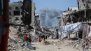 Asap mengepul ke arah utara menjadi latar ketika warga Palestina bergerak melalui Jabalia meninggalkan Jalur Gaza utara menuju Kota Gaza pada 19 Mei 2025. (Bashar TALEB/AFP)