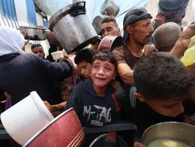 Salah satu anak Palestina menangis saat menunggu pembagian makanan di sebuah titik distribusi di Nuseirat, Jalur Gaza Tengah, pada 11 Juni 2025. (Eyad BABA/AFP)
