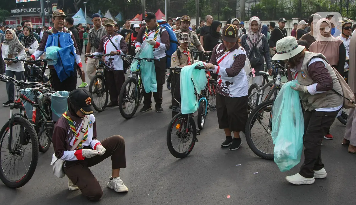 Anggota Praja Muda Karana (Pramuka) menggunakan sepeda bermuatan tong sampah memunguti sampah di jalanan arena car free day (CFD) kawasan Bundaran Hotel Indonesia, Jakarta, Minggu (9/6/2024). (merdeka.com/Arie Basuki)