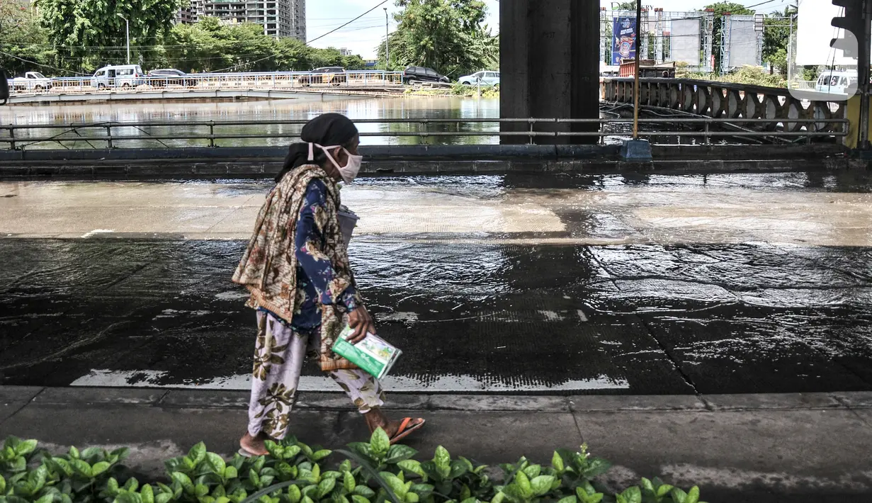 Warga berjalan dekat banjir yang menggenangi Jalan RE Martadinata, Ancol, Jakarta, Selasa (9/11/2021). Banjir disebabkan oleh meluapnya Kali Ciliwung Gunung Sahari dan ditambah fenomena air pasang laut yang terus terjadi. (merdeka.com/Iqbal S. Nugroho)