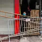 Seorang wanita melihat dari balik barikade improvisasi yang terbuat dari papan kayu dan tangga untuk membatasi pergerakan warga di Hanoi, pada 30 Agustus 2021. Tiang bambu, peti bir, tangga dan kursi rusak: benda sehari-hari membentuk barikade sementara saat lockdown Covid-19. (Manan VATSYAYANA/AFP)