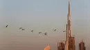 Burung flamingo terbang bermigrasi melewati gedung tertinggi di dunia, Burj Khalifa di Dubai, Uni Emirat Arab (28/1). Meski terdiri dari gedung-gedung mewah, pemerintah Dubai tetap menjaga habitat burung flamingo. (AP Photo / Kamran Jebreili)