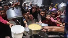 Para pengungsi Palestina berkumpul untuk mengambil makanan yang sudah dimasak dalam sebuah pembagian makanan di Jabalia, Jalur Gaza utara, pada 19 Mei 2025. (Bashar TALEB/AFP)