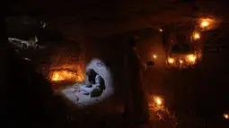 Seorang pria membaca ayat suci Al-Quran di makam kerabatnya di pemakaman Wadi al-Salam, di Najaf, selatan Baghdad, Irak, 28 Juli 2016. Pemakaman tersebut sudah ada sejak 1.400 tahun lalu. (REUTERS/Alaa Al-Marjani)