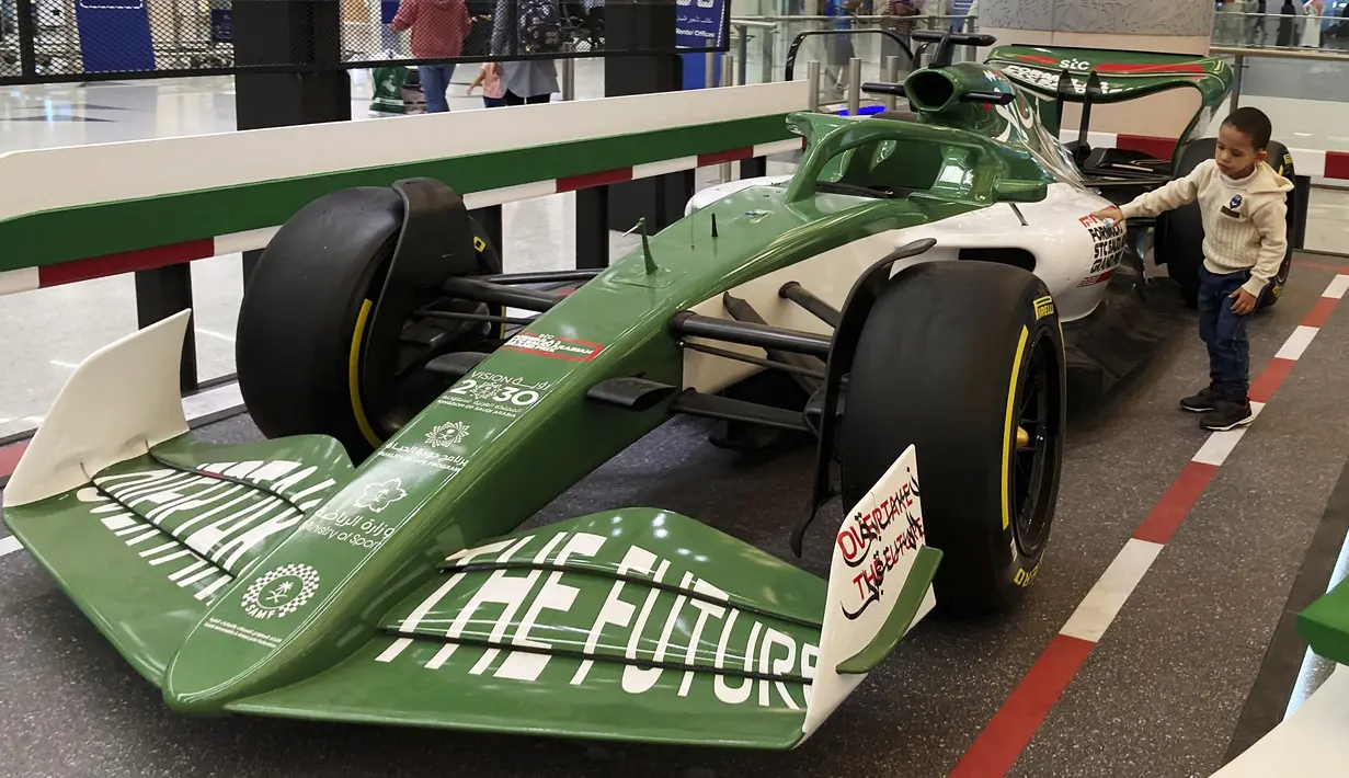 Seorang anak memeluk mobil balap yang mempromosikan Formula One (F1), di Bandara Internasional King Abdulaziz di Jeddah, Arab Saudi, Selasa (30/11/2021). Arab Saudi untuk pertama kalinya dipercaya menjadi tuan rumah balapan F1 2021, yang akan berlangsung 3-5 Desember mendatang. (AP Photo/Amr Nabil)