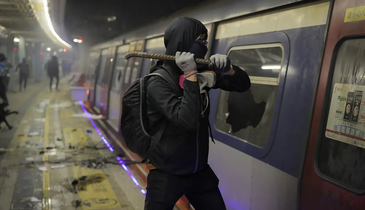 Seorang siswa menggunakan linggis merusak sebuah kereta di dalam stasiun MTR Universitas China di Hong Kong (13/11/2019). Gerakan antipemerintah Hong Kong yang telah berlangsung selama lima bulan bertindak semakin keras. (AP Photo/Kin Cheung)