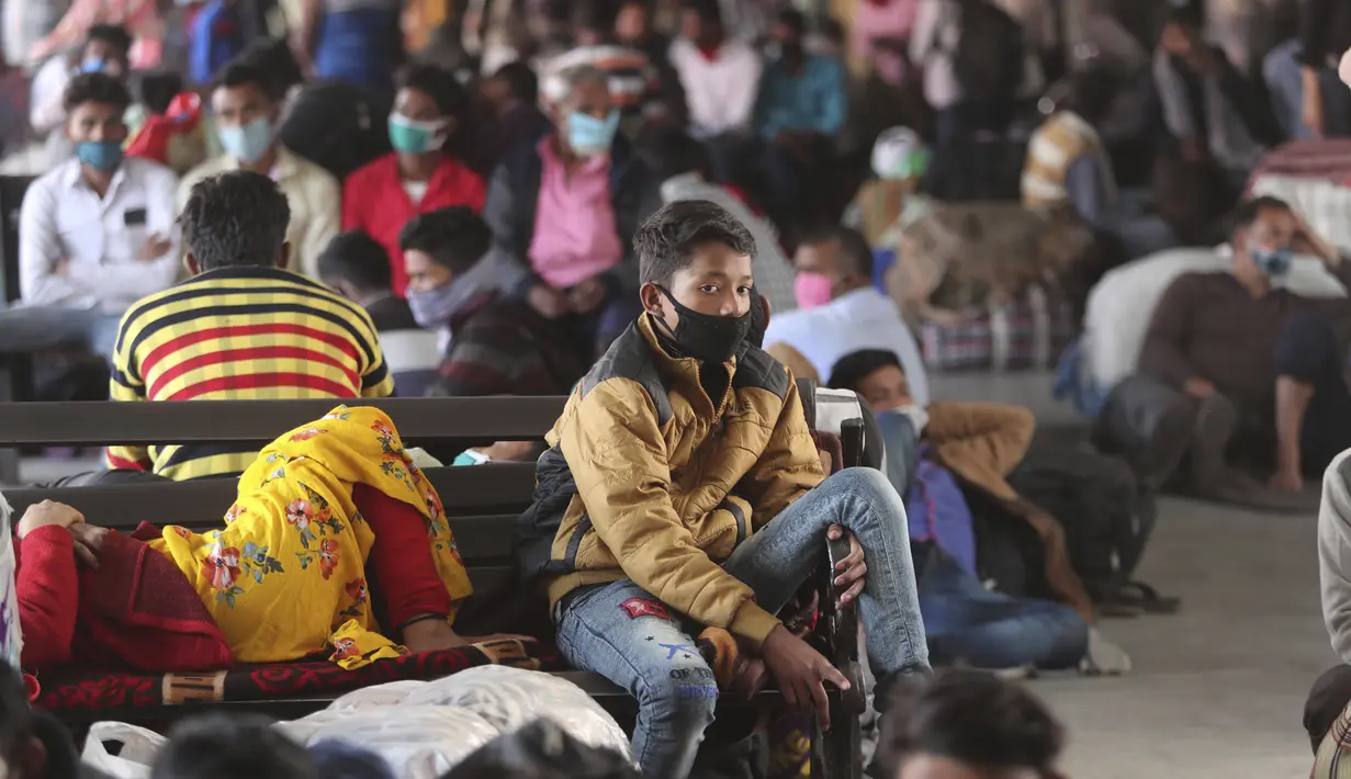 Orang-orang yang memakai masker sebagai antisipasi terhadap virus corona menunggu transportasi di terminal bus di Jammu, India (26/3/2021). Negara bagian Maharashtra tengah, tempat ibu kota keuangan India, Mumbai, menyumbang lebih dari separuh infeksi baru.  (AP Photo/Channi Anand)