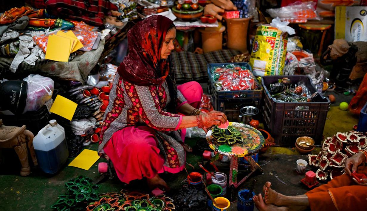Seorang pembuat tembikar menjual lampu tanah jelang Festival Diwali di sepanjang pinggir jalan di New Delhi, India, 18 Oktober 2022. Festival Diwali atau dalam agama Hindu berarti Festival Cahaya melambangkan kemenangan baik atas keburukan, dan lampu atau pelita dinyalakan sebagai tanda perayaan serta harapan umat manusia. (Sajjad HUSSAIN/AFP)