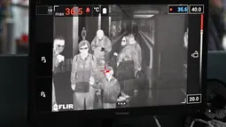 Petugas kesehatan memantau suhu tubuh penumpang yang tiba dengan 'thermal scanner' di Bandara Internasional Kuala Lumpur, Sepang, pada Selasa (21/1/2020). Pemerintah Malaysia mulai mengoperasikan alat pemindai suhu tubuh merespons penyebaran virus korona yang kian masif di China. (MOHD RASFAN/AFP)