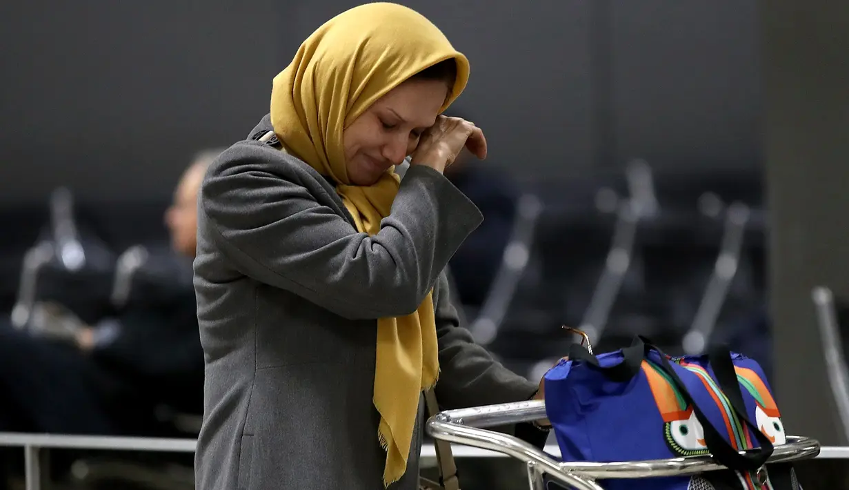 Wanita muslim menangis terharu setelah berpergian dari Addis Ababa, Ethiopia setibanya ia di Bandara Dulles, Washington, Senin (6/2). Sejumlah warga muslim sempat tidak dapat masuk AS akibat kebijakan imigrasi Donald Trump. (Win McNamee/Getty Images/AFP)