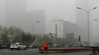 Petugas membersihkan jalanan saat diselimuti kabut asap tebal di Beijing, China (14/11). Pihak berwenang mengeluarkan peringatan kuning untuk polusi udara buruk pada hari Rabu. (AP Photo/Andy Wong)