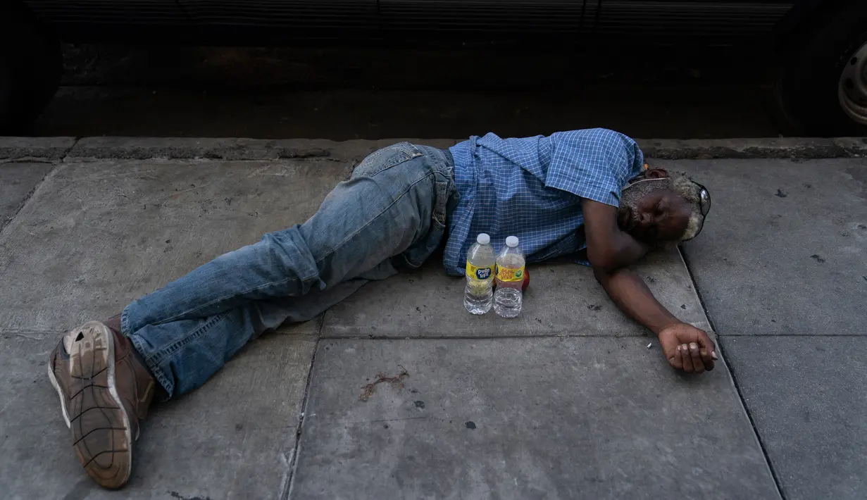 Seorang pria tunawisma tidur siang di trotoar dengan dua botol air di depannya di daerah Skid Row Los Angeles, Rabu (31/8/2022). Peringatan panas berlebihan meluas ke seluruh California Selatan dan ke utara ke Central Valley pada Rabu , dan diperkirakan akan menyebar ke California Utara pada akhir minggu ini. (Foto AP/Jae C.Hong)