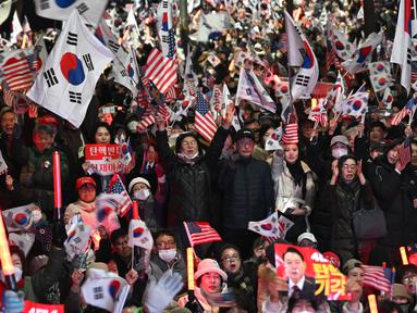 Para pendukung Yoon Suk Yeol melambaikan bendera Korea Selatan dan Amerika Serikat dalam sebuah unjuk rasa di dekat kediaman presiden di Seoul pada tanggal 8 Maret 2025, setelah iring-iringan mobil yang membawa Yoon tiba di kediaman tersebut. (Jung Yeon-je/AFP)