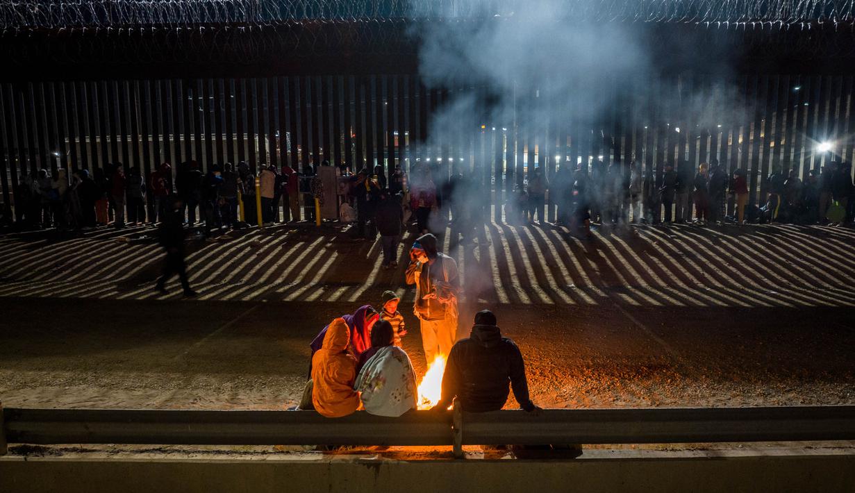 Migran bermalam di luar, di sepanjang pagar perbatasan AS-Meksiko sambil menunggu pengajuan suaka di Ciudad Juarez, Meksiko, Rabu (21/12/2022). Seharusnya pada tanggal 21 Desember 2022 AS resmi mencabut pembatasan pengungsi karena alasan pandemi Covid-19, namun Mahkamah Agung justru mengumumkan akan tetap membiarkan kebijakan Judul 42 tetap berlaku. (JOHN MOORE / GETTY IMAGES NORTH AMERICA / Getty Images via AFP)