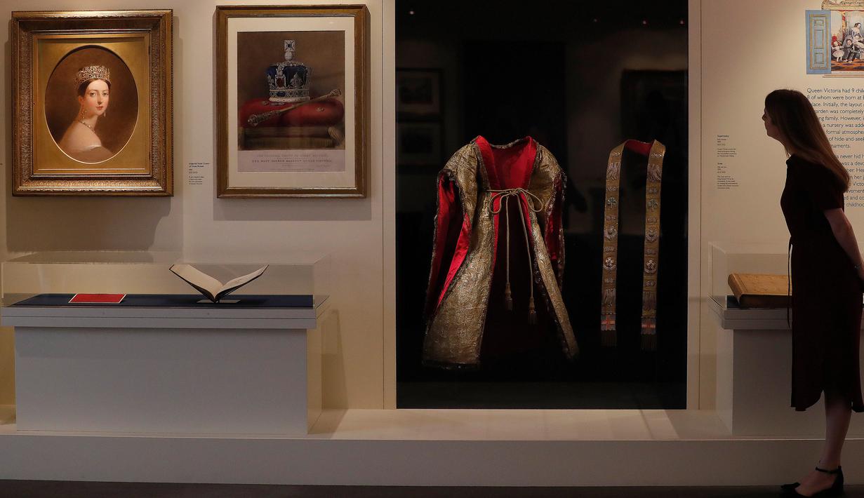 Seorang wanita melihat gaun upacara yang dikenakan Ratu Victoria pada upacara penobatannya tahun 1838 sebagai bagian dari pameran di Istana Buckingham, London, Rabu (17/7/2019). Pameran yang dibuka pada 20 Juli itu menandai peringatan 200 tahun kelahiran Ratu Victoria. (AP Photo/Frank Augstein)
