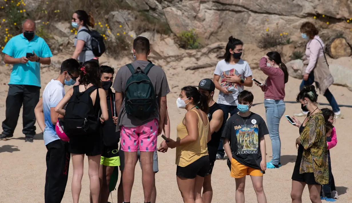 Orang-orang menikmati hari yang cerah di pantai Sa Conca di Castell-Platja D'Aro dekat Girona, Spanyol pada Rabu (31/3/2021). Masker telah wajib digunakan di Spanyol sejak Mei 2020 namun hanya di tempat yang tidak memungkinkan menjaga jarak minimal 2 meter. (Josep LAGO / AFP)