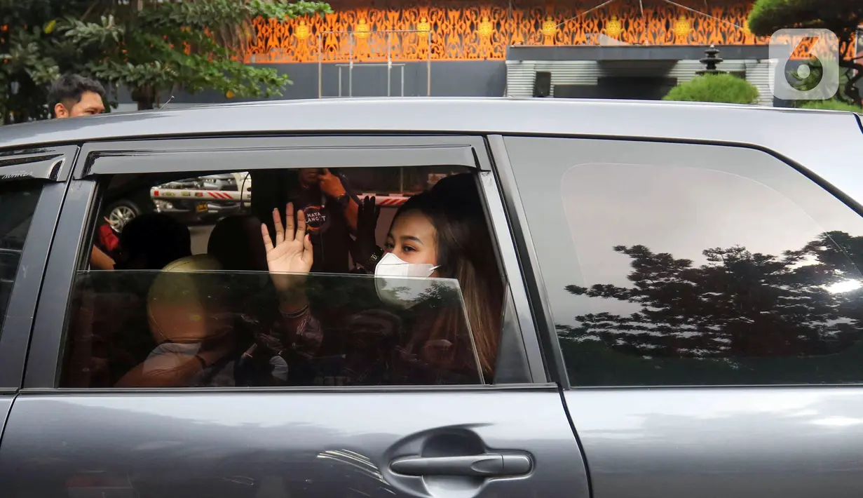 Adik mendiang Vanessa Angel, Mayang Lucyana Fitri melambaikan tangan dari dalam mobil usai menjalani pemeriksaan di Direktorat Reserse Kriminal Khusus Polda Metro Jaya, Jakarta, Rabu (8/6/2022). Mayang menjalani pemeriksaan kedua terkait kasus dugaan pencemaran nama baik yang dilaporkan produk skincare. (Liputan6.com/Herman Zakharia)