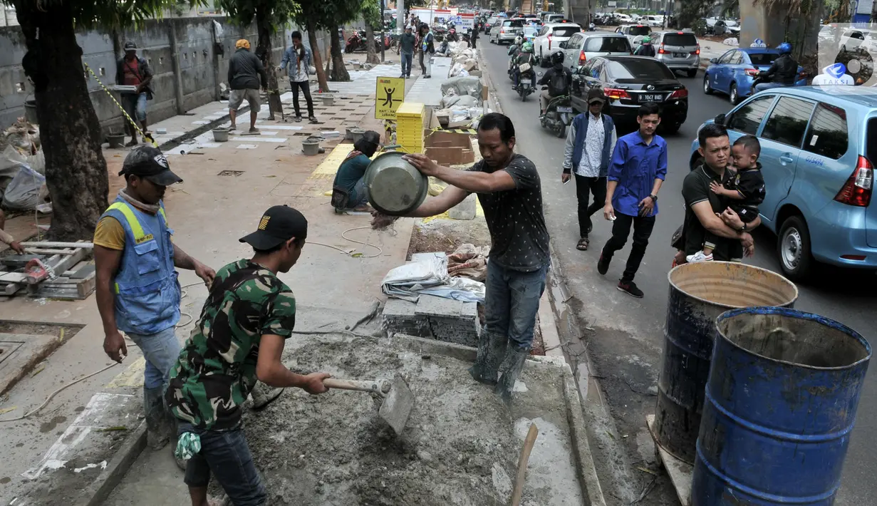 Pekerja menyelesaikan proyek revitalisasi trotoar di kawasan Kuningan, Jakarta, Senin (4/11/2019). Dinas Bina Marga DKI Jakarta menganggarkan biaya proyek revitalisasi trotoar sebesar Rp 1,1 triliun. (merdeka.com/Iqbal Nugroho)