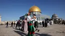Umat Muslim merayakan setelah sholat Idul Fitri pagi, menandai akhir bulan suci Ramadhan, di luar masjid Kubah Batu di kompleks masjid Al-Aqsa di Yerusalem Tua (13/5/2021). (AFP/Ahmad Gharabli)
