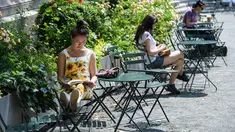 Orang-orang duduk di bawah sinar matahari pada hari yang hangat di Bryant Park di New York City (7/6/2021). Cuaca yang hangat di New York dimanfaatkan warga untuk membaca buku hingga berjalan-jalan. (AFP/Angela Weiss)
