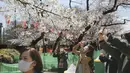Orang-orang yang memakai masker mengambil foto bunga sakura di Tokyo, Selasa (23/3/2021). Mendekati musim semi dan mekarnya bunga sakura, banyak pemerintah daerah yang terus meminta warganya untuk tidak mengadakan pesta melihat bunga sakura (hanami). (AP Photo/Koji Sasahara)