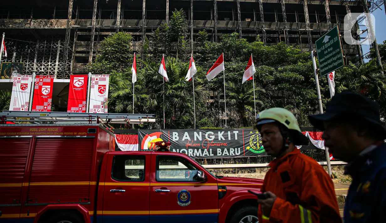 Petugas pemadam kebakaran melintas di depan gedung utama Kejaksaan Agung yang terbakar di Jakarta, Minggu (23/8/2020). Kebakaran yang berawal sejak Sabtu (22/8) malam itu, baru bisa dikuasai pagi ini, Minggu (23/8). (Liputan6.com/Faizal Fanani)