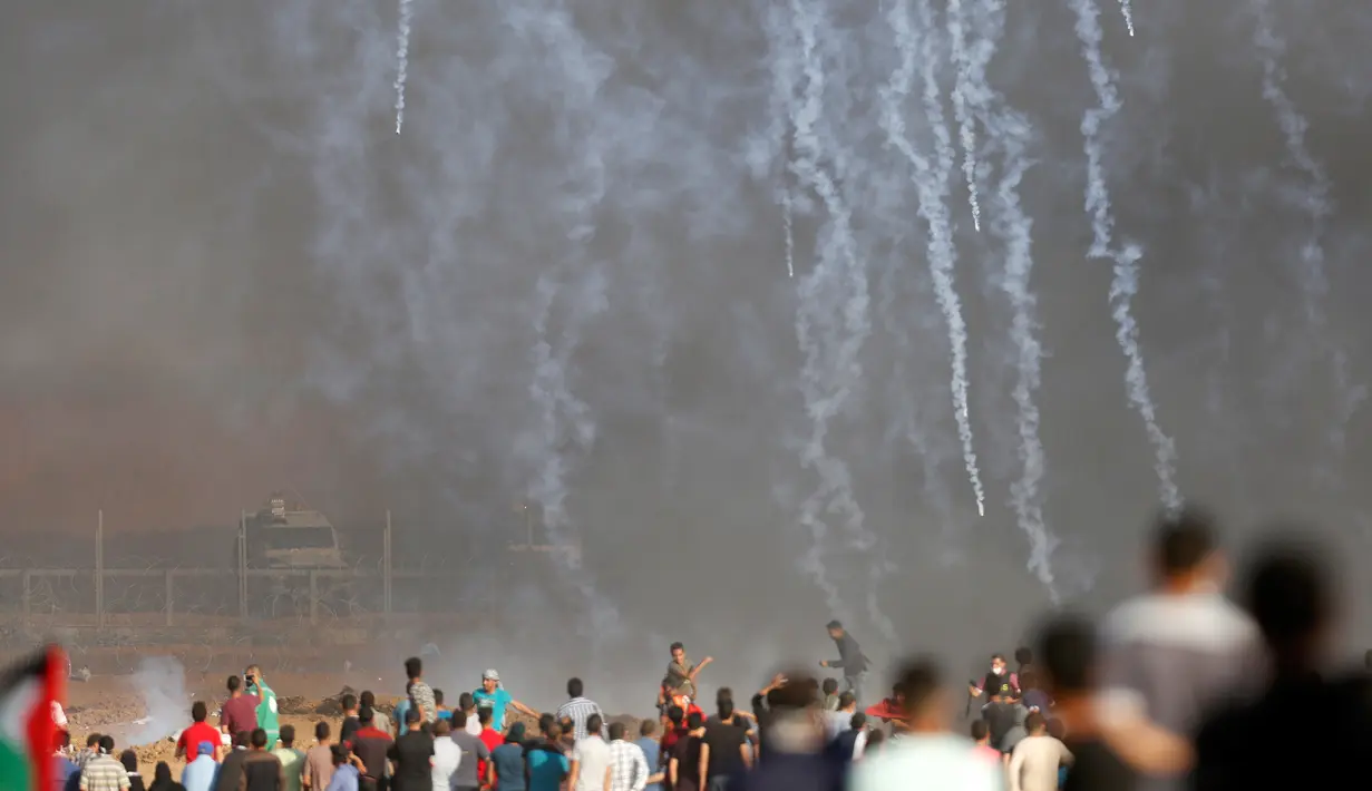 Pasukan Israel menembakkan gas air mata ke arah demonstran Palestina selama bentrokan di perbatasan jalur Gaza (11/5). Warga Palestina menggelar aski yang berujung bentrokan di perbatasan jalur Gaza. (AFP Photo/Mohammed Abed)