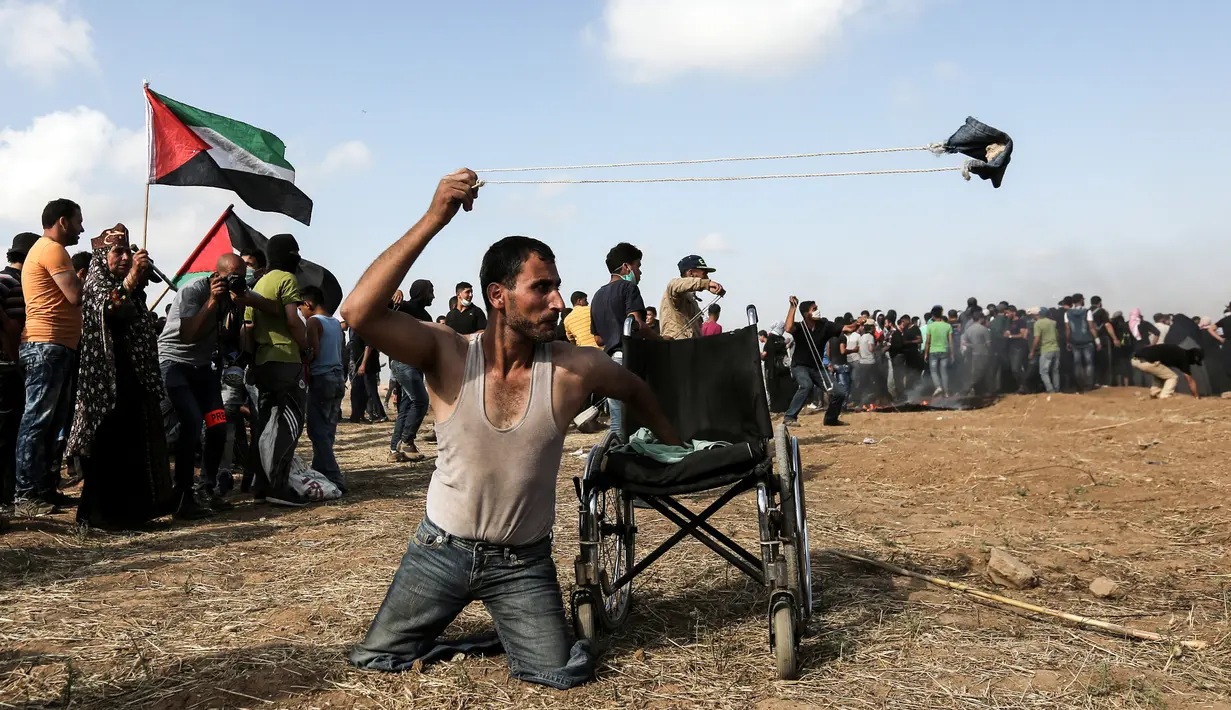 Seorang pria Palestina bernama Saber al-Ashkar melemparkan batu saat bentrokan dengan pasukan Israel di jalur Gaza (11/5). Meski tidak memiliki kaki, Saber turut ikut bertempur melawan pasukan Israel. (AFP/Mahmud Hams)