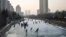 Sejumlah warga tampak menikmat bermain ice skating atau seluncur es di atas sungai yang telah membeku di Beijing, Jumat (1/1). Semenjak membeku, sungai di Beijing ini menjadi objek wisata es dadakan yang banyak diminati wisatawan.  (AFP/Fred Dufour) 