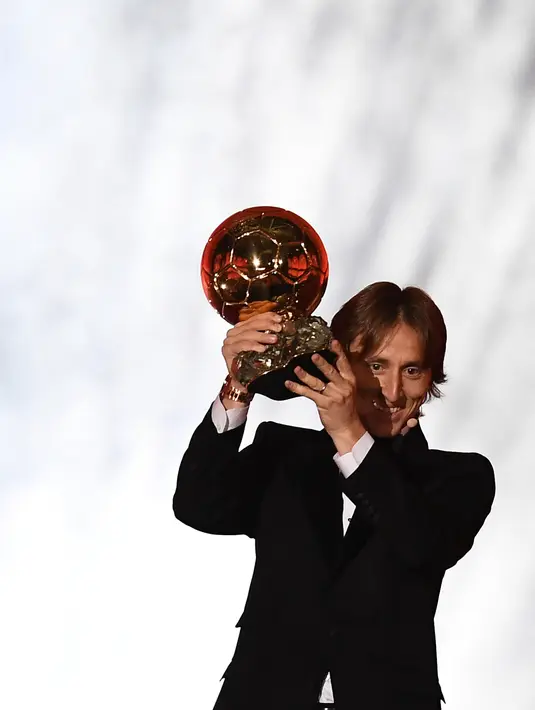 Gelandang Real Madrid, Luka Modric mengangkat trofi setelah memenangkan penghargaan Ballon d'Or 2018 di Grand Palais, Paris, Senin (3/12). Modric sukses memutus dominasi Cristiano Ronaldo dan Lionel Messi yang bertahan selama satu dekade (FRANCK FIFE/AFP)