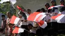 Anak-anak sekolah mengibarkan bendera Merah-Putih saat memberian semangat kepada para pebalap pada Tour de Singkarak 2016, di Sumatera Barat, (12/8/2016). (Bola.com/Nicklas Hanoatubun)