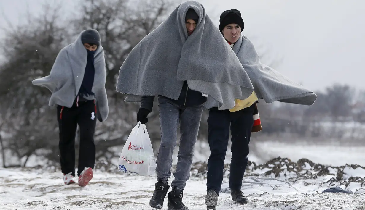 Sejumlah imigran berjalan dengan menutupi tubuhnya dengan kain setelah melintasi hamparan salju dari perbatasan Macedonia di dekat desa Miratovac, Serbia, (18/1/2016). (REUTERS/Marko Djurica)