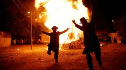 Dua orang Yahudi Ultra-Ortodoks menari di samping api unggun selama perayaan hari libur Yahudi Lag Ba-Omer di Shearim, Yerusalem, (25/5). Hari libur Yahudi ini terjadi pada hari ke-18 dari bulan Ibrani dari Iyar. (REUTERS/Ronen Zvulun)