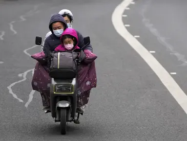 Sebuah keluarga mengendarai skuter bertenaga listrik di sebuah jalan di Beijing, China, Minggu (9/1/2022). Tianjin memulai pengujian massal terhadap 14 juta penduduknya setelah sekelompok anak-anak dan orang dewasa dinyatakan positif COVID-19, beberapa dengan varian omicron. (AP Photo/Andy Wong)
