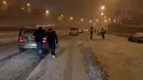 Warga mendorong mobil yang terjebak salju tebal di Jalan Lingkar M30, Madrid, Spanyol, Jumat (8/1/2021). Otoritas Madrid mengimbau warga untuk menghindari perjalanan yang tidak penting akibat Badai Filomena. (OSCAR DEL POZO/AFP)