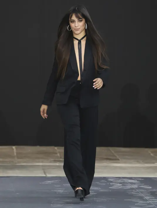 Camila Cabello berjalan di catwalk memakai kreasi dari koleksi L'Oreal Ready To Wear Spring-Summer 2020 selama pekan mode di Paris (28/9/2019). Camila Cabello mengenakan pita hitam untuk menutupi dadanya yang tidak mengenakan bra. (Photo by Vianney Le Caer/Invision/AP)