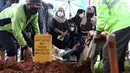 Istri mantan penggawa Timnas Indonesia Ricky Yacobi, Harly Ramayani (duduk tengah) menyaksikan proses pemakaman suaminya di TPU Tanah Kusir, Jakarta, Sabtu (21/11/2020). Ricky Yacobi meninggal dunia pada Sabtu (21/11) akibat serangan jantung pada usia 57 tahun. (Liputan6.com/Helmi Fithriansyah)