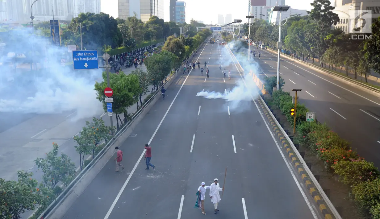 Massa menghindari gas air mata saat bentrok dengan polisi di jalan tol dalam kota di kawasan Slipi, Jakarta, Rabu (22/5/2019). Jalan tol dalam kota sempat ditutup sekitar setengah jam, dan massa dihalau petugas ke arah kemanggisan. (merdeka.com/Arie Basuki)