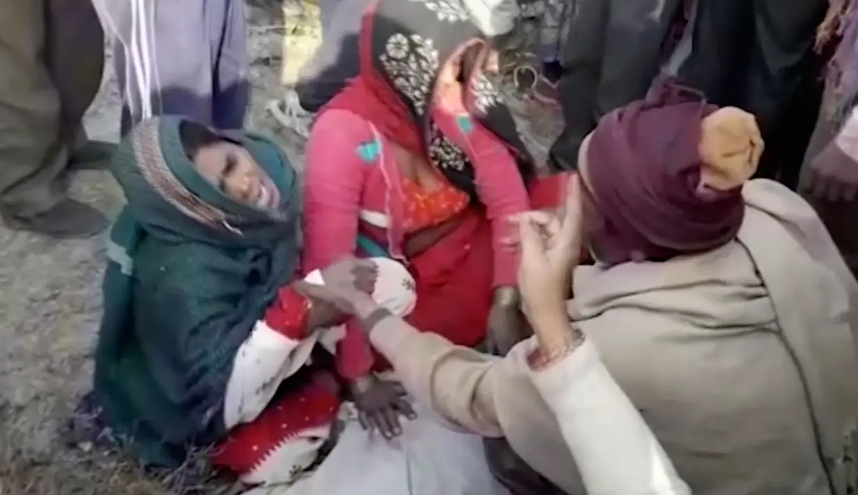Keluarga menangis di atas jasad korban kecelakaan antara bus sekolah dan truk di Etah, negara bagian Uttar Pradesh, India, Kamis (19/1). Butuh satu jam untuk mengevakuasi jenazah dan juga korban luka-luka dari badan bus yang ringsek (KK Production via AP)