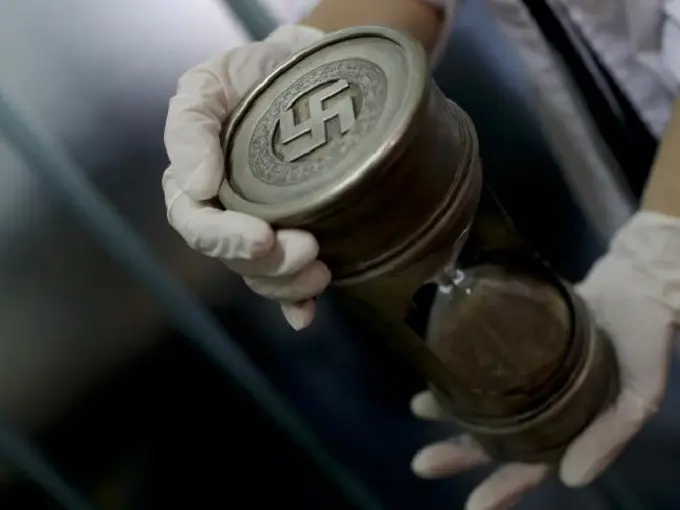 Seorang anggota polisi Argentina memegang jam pasir dengan logo Nazi (AP)