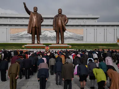 Orang-orang membungkuk ketika mereka memberi penghormatan kepada patung-patung pemimpin Korea Utara Kim Il Sung dan Kim Jong Il di Pyongyang (15/4). Mereka melakukan penghormatan untuk memperingati ulang tahun Kim Il Sung.  (AFP Photo/Ed Jones)