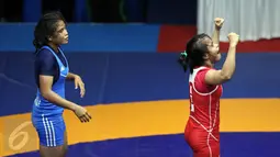 Pegulat putri Kaltim, Inadrah (kostum merah) mengangkat tangan usai memastikan menang melawan pegulat Sumbar Mardiatul di final gaya bebas kelas 53 kg putri pada PON XIX di Arena Saparua Sport Park, Bandung, Sabtu (24/9). (Liputan6.com/Helmi Fithriansyah)