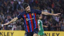 Pemain Barcelona, Robert Lewandowski, melakukan selebrasi setelah mencetak gol ke gawang Real Betis pada laga Liga Spanyol di Stadion Camp Nou, Minggu (30/4/2023). Barca menang telak 4-0 atas Betis. (AP Photo/Joan Monfort)