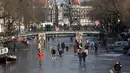 Orang-orang berseluncur dan berjalan melintasi permukaan kanal Prinsengracht yang membeku di Amsterdam, Belanda, Jumat (2/3). Udara dingin membuat air yang biasanya mengalir di Prinsengracht berubah total menjadi lapisan es tebal. (AP/Mike Corder)